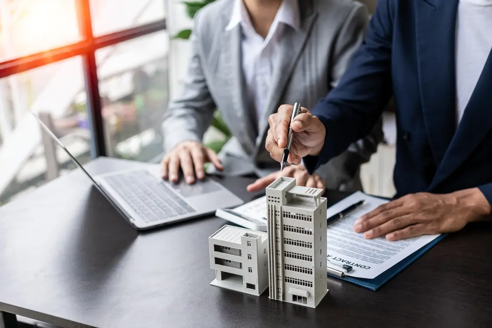 Two business professionals discuss a building model's design.