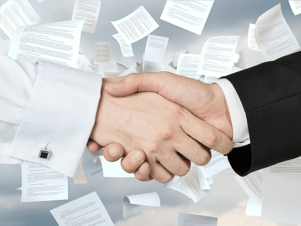 Two business professionals shake hands in front of a background of floating legal documents.