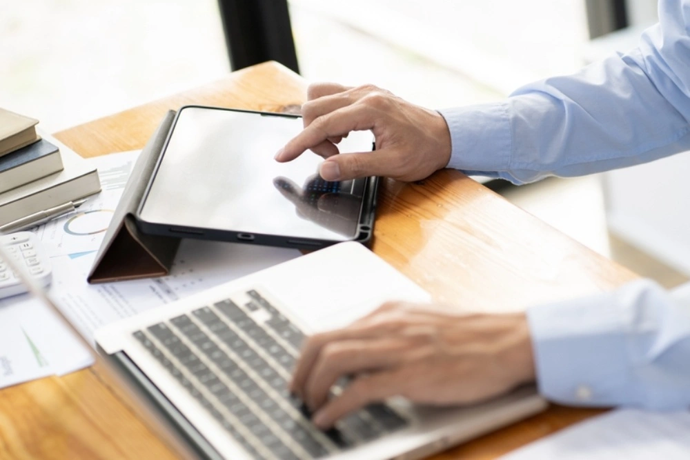 Property manager reviewing reports on tablet and laptop